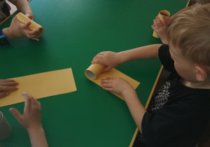 Dzieci oklejają rolkę po papierze toaletowym kolorowym papierem